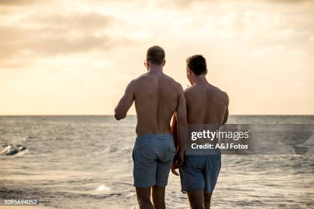 young homosexual couple walking on the beach - gay cuba stock pictures, royalty-free photos & images