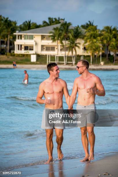 young homosexual couple walking on the beach - gay cuba stock pictures, royalty-free photos & images