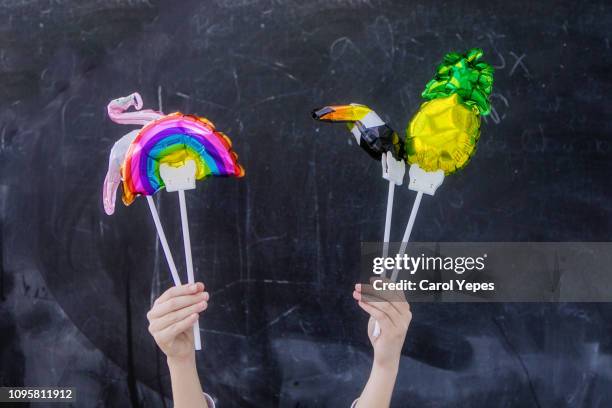 child hand holding a bunch of balloons in black background - helium stock pictures, royalty-free photos & images