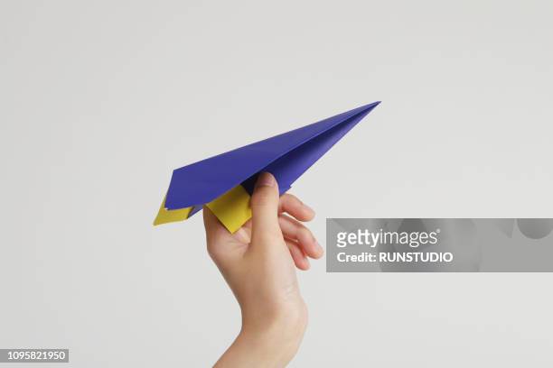 hand holding blue paper airplane - origami spiel stock-fotos und bilder