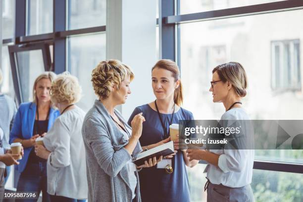 women talking during coffee break at convention center - press conference imagens e fotografias de stock