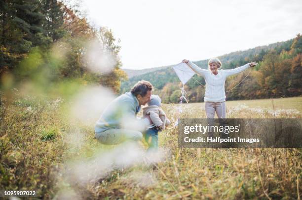 senior grandparents outdoors and toddler granddaughter with a kite in nature. - kite toy foto e immagini stock
