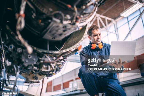 fluggerätmechaniker tun einige diagnose auf einem laptop neben einer jet-engine in einen flugzeughangar - flugzeugtriebwerk stock-fotos und bilder