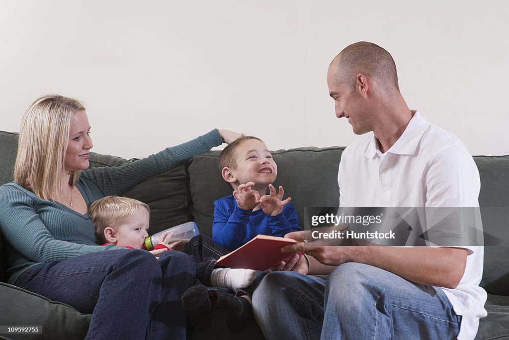 Boy signing the word 'Family' in American Sign Language while studying with his parents