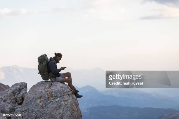 hiker with mobile phone and backpack - outdoor guy sitting on a rock stock pictures, royalty-free photos & images
