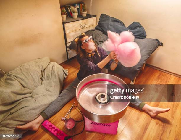 junge frau, die zu hause essen zuckerwatte - zuckerfest stock-fotos und bilder