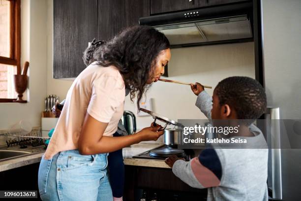 mama ruft den ersten geschmack - black mother and child cooking stock-fotos und bilder