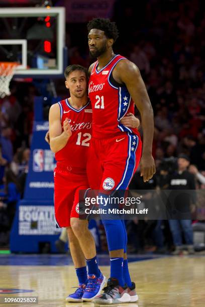 McConnell of the Philadelphia 76ers hugs Joel Embiid at the end of the first quarter against the Denver Nuggets at the Wells Fargo Center on February...