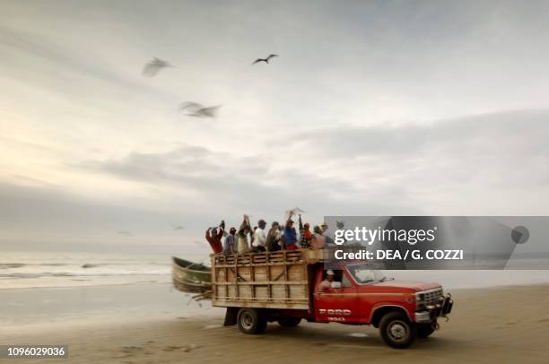 Truck on the beach and a group of fishermen, near Montanitas, Guayas Province, Ecuador.