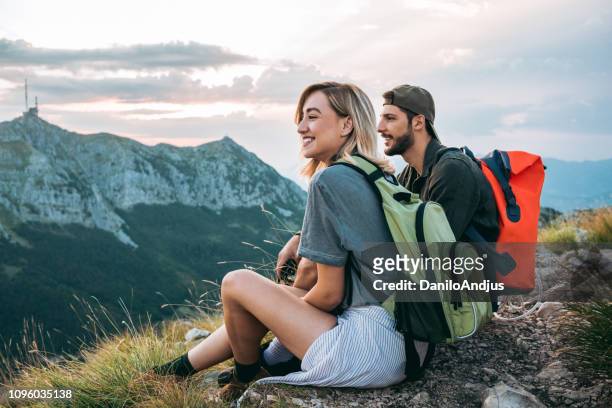 hermosa joven pareja relajante después de hacer senderismo y tomar un descanso - felicidad fotografías e imágenes de stock