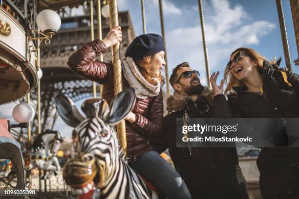 friends having fun on carousel at paris - paris autumn stock pictures, royalty-free photos & images