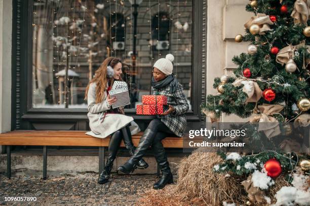 two young women shopping for christmas - exchanging gifts stock pictures, royalty-free photos & images