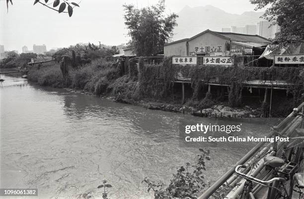 Stream in Tuen Mun with some shops on the bank. The 30-foot-wide stream will be transformed into a 180-foot-wide riverbed. 05OCT77