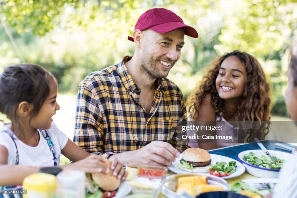 Happy father and daughters enjoying barbecue lunch