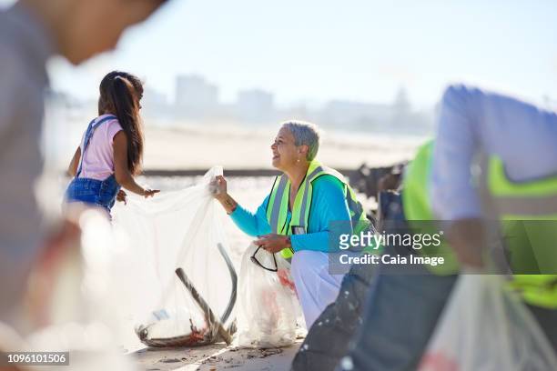 Senior woman and girl volunteer cleaning up litter on sunny beach