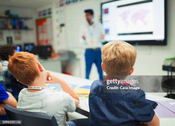 junior high school boys watching teacher during lesson in classroom - caiaimage stock-fotos und bilder