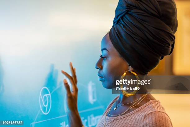 mujer joven afroestadounidense con pantalla interactiva - turbante fotografías e imágenes de stock