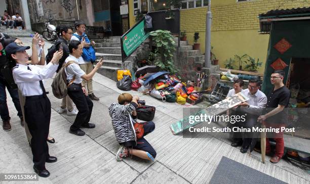 People take photos of Ho Hee-kee's family as staffs from Food and Environmental Hygiene Department dismantle the makeshift roadside umbrella repair...