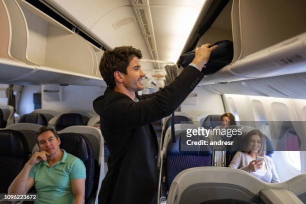 glada passagerare att sätta hans handbagage i den overhead facket - male flight attendant bildbanksfoton och bilder