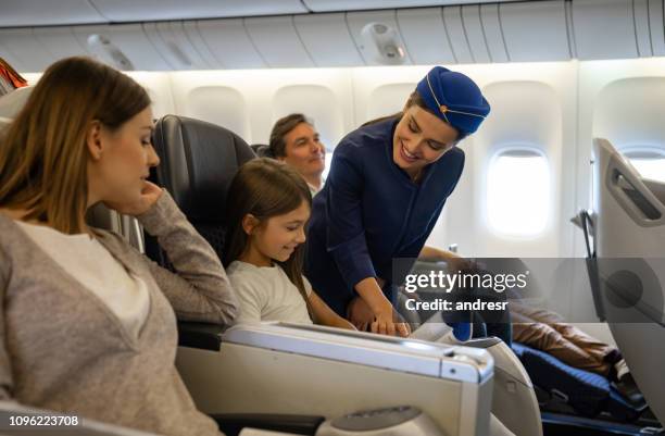 friendly flight attendant helping a girl in an airplane - air hostess stock pictures, royalty-free photos & images