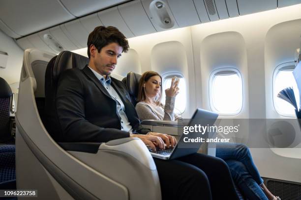 homme d’affaires voyageant par avion et travaillant sur son ordinateur portable - business travel photos et images de collection