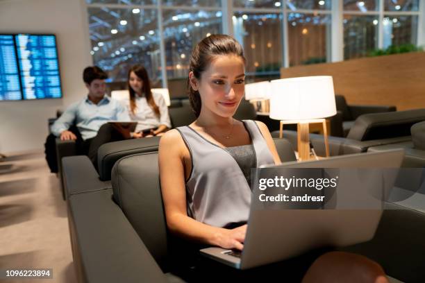 reizende zakenvrouw online werken op de luchthaven - vertrekhal stockfoto's en -beelden