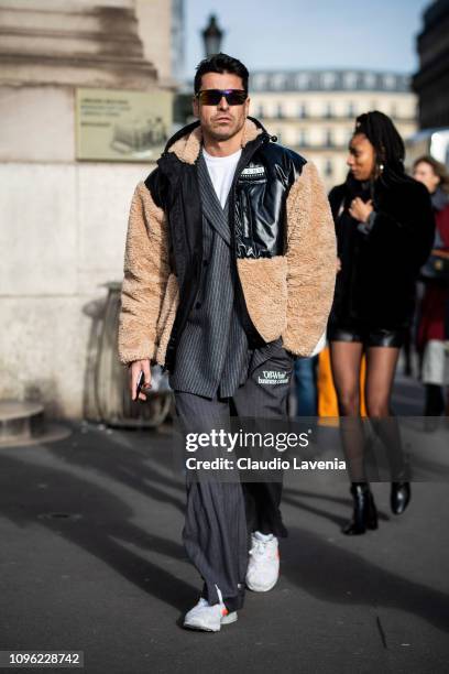 Alex Badia, wearing a black jacket with fur details, grey striped blazer, grey Off-White pants and white shoes, is seen in the streets of Paris...