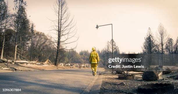 one firefighter wearing bright yellow protective gear and helmet walks alone along a street where every home burned to the ground, paradise fire 2018 - force of nature bildbanksfoton och bilder