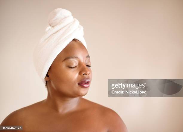 female with towel wrapped on her head against brown background. - curvy african women stock pictures, royalty-free photos & images