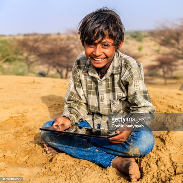 happy young indian boy using digital tablet, desert village, india - local gypsy stock pictures, royalty-free photos & images