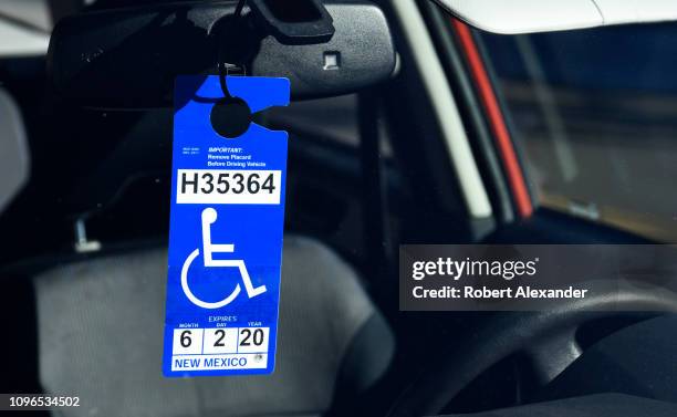 Handicapped driver placard hangs on the rearview mirror of a car parked in a handicapped parking space in Santa Fe, New Mexico.