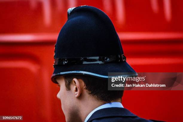 london bobby in front of red double-decker bus - police hat stock pictures, royalty-free photos & images