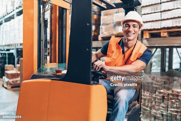 fröhliche lagerarbeiter mit einem gabelstapler - gabelstapler stock-fotos und bilder