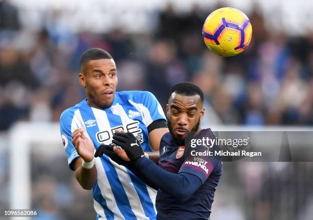 Mathias Zanka Jorgensen of Huddersfield Town battles for possession in the air with Alexandre Lacazette of Arsenal during the Premier League match...