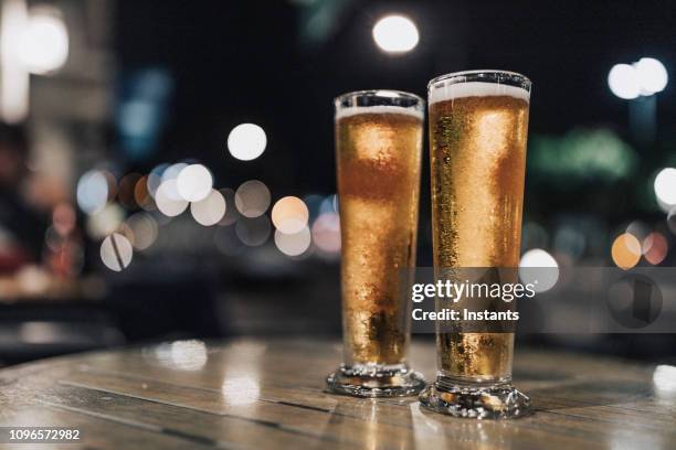 erschossen in der nacht, draußen, nahaufnahme von zwei kaltes bier in einem der fort de france sidewalk café-bars. - terrasse de café stock-fotos und bilder