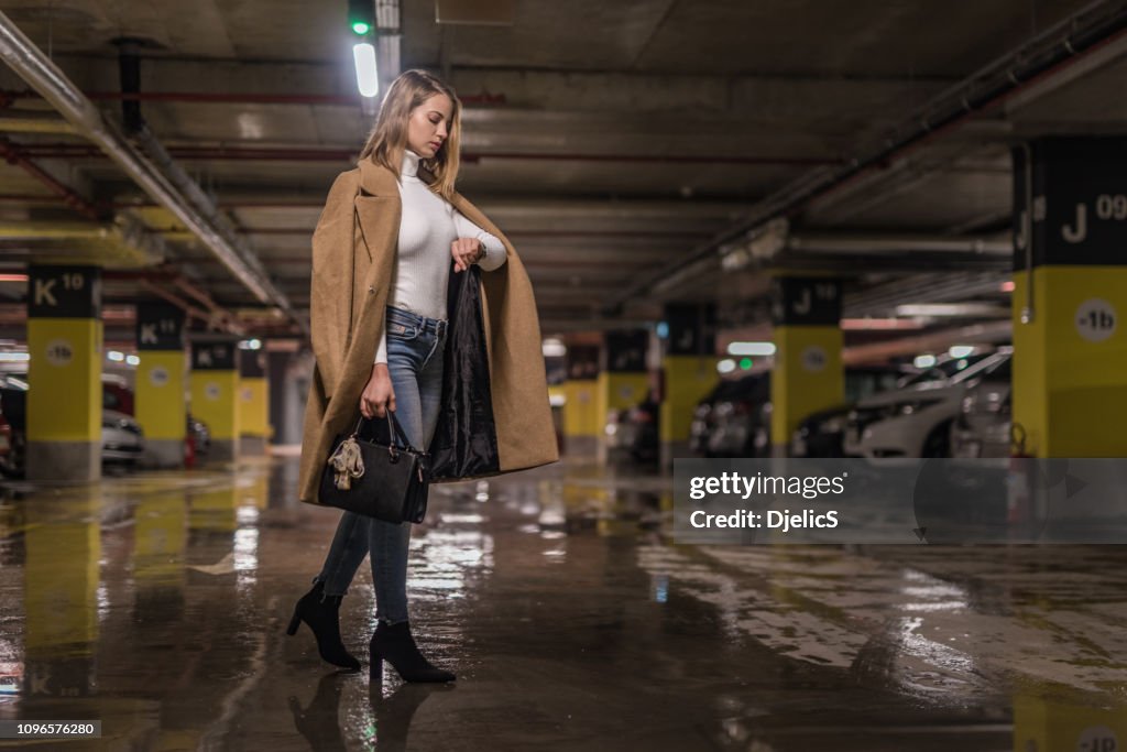 Moda joven comprobación de tiempo en un garaje público.