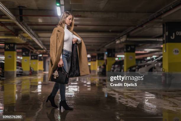 giovane donna alla moda che controlla l'orario in un garage pubblico. - cool cars foto e immagini stock