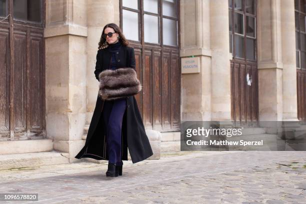 Guest is seen on the street during Men's Paris Fashion Week AW19 wearing black wool coat with navy outfit and fur muff on January 19, 2019 in Paris,...