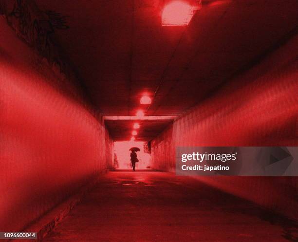 a woman walking alone through a dark tunnel - raped women fotografías e imágenes de stock