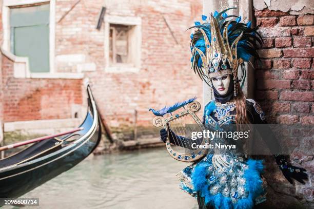 frau mit saiteninstrument in attraktiven goldenen und blauen kostüm im karneval von venedig - masked musicians stock-fotos und bilder