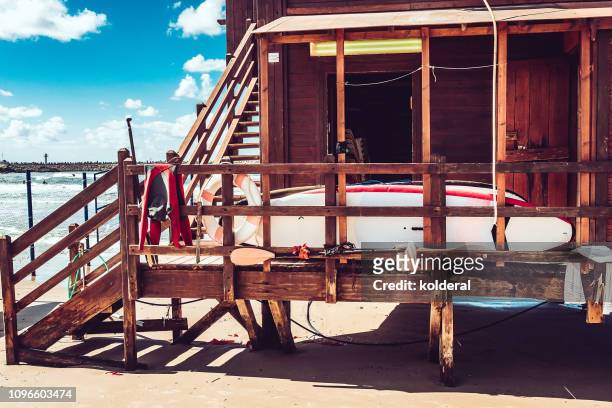 lifeguard hut with surfboard against blue sky on mediterranean beach - surf life saving stockfoto's en -beelden