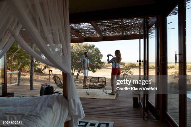 couple photographing each other at arrival of exclusive cabin - safari lodge stock pictures, royalty-free photos & images