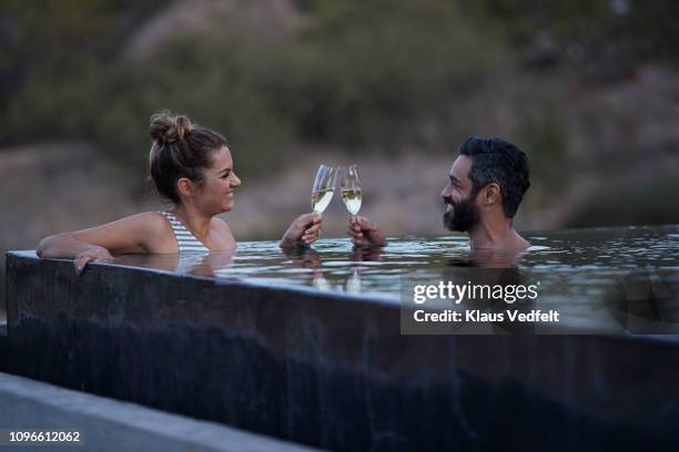 couple toasting in champagne in infinity pool on safari lodge - hot tub stock pictures, royalty-free photos & images