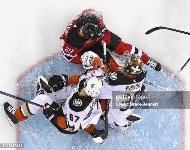 Rickard Rakell and John Gibson of the Anaheim Ducks defend against Kyle Palmieri of the New Jersey Devils at the Prudential Center on January 19,...