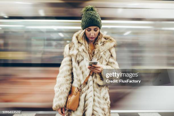 verdrietig meisje met haar telefoon terwijl staande op een metro platform - metro platform stockfoto's en -beelden