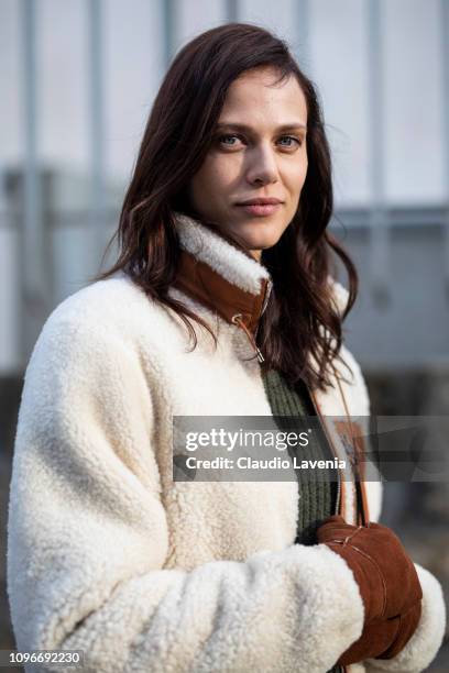 Aymeline Valade, wearing a white fur jacket with brown leather details, brown gloves and blue jeans, is seen in the streets of Paris after the Loewe...