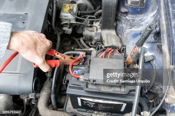 man charging a car battery with a jumper cable - cable car fotografías e imágenes de stock