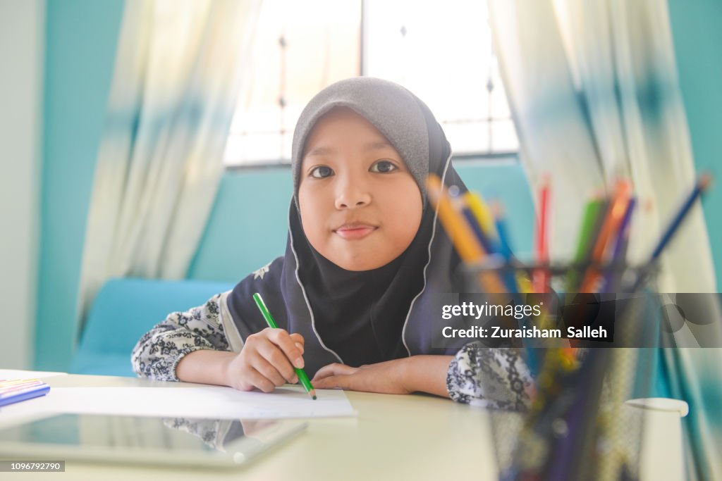Asiatisk tjej gör läxor med digital tablett hemma