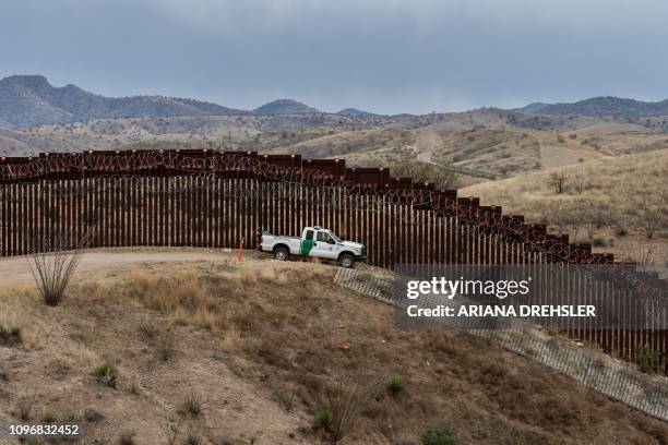 Border Patrol officer sits inside his car as he guards the US/Mexico border fence, in Nogales, Arizona, on February 9, 2019.