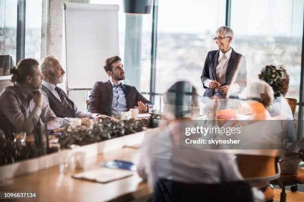 happy female leader giving a speech to large group of business people in a board room. - presenter stock pictures, royalty-free photos & images